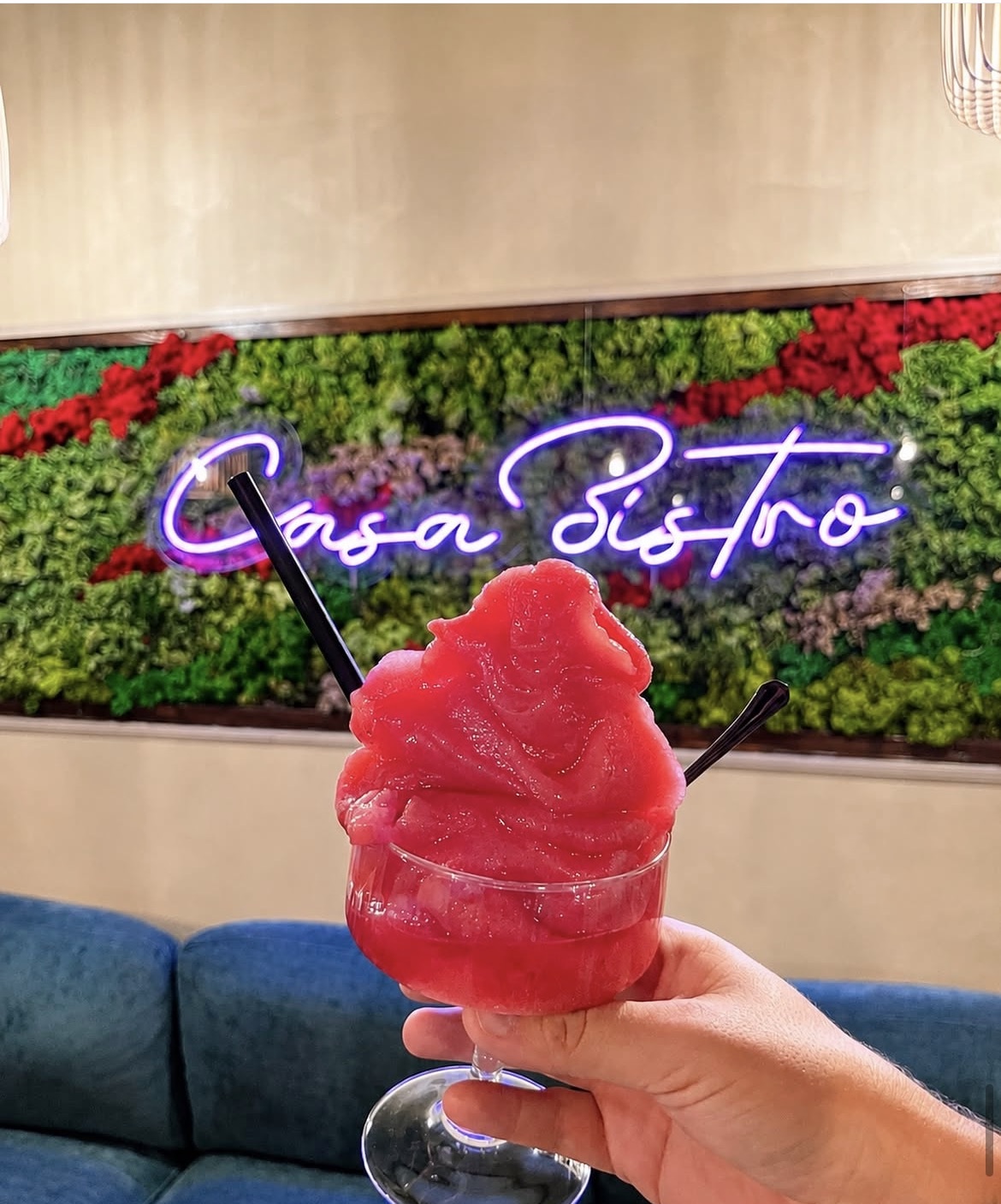 Cóctel de Casa Bistro frente al neón del local
